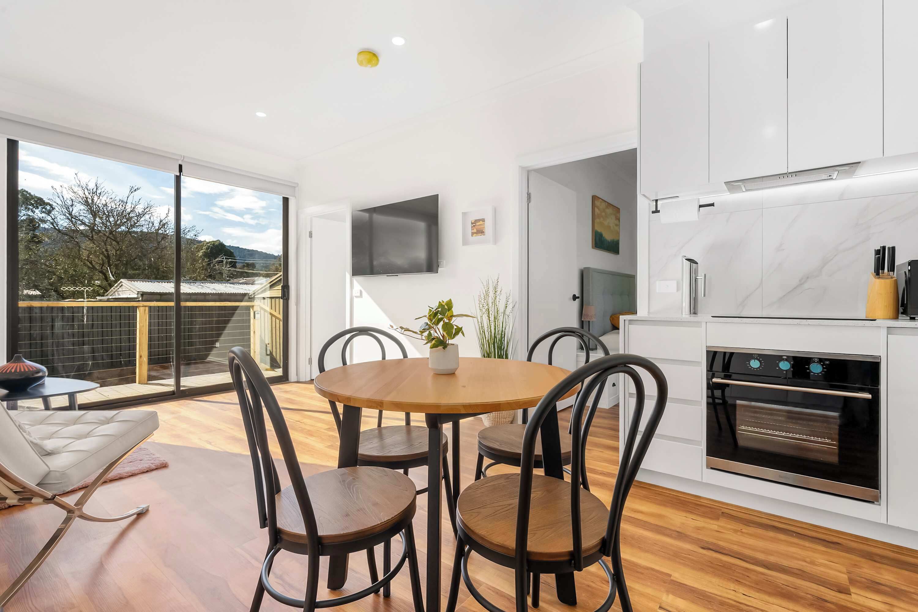 A modern kitchen with a built-in oven and a dining area with a round table and chairs.
