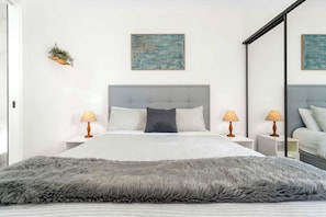 A modern bedroom with a large bed, two bedside lamps, a grey furry throw, and two abstract paintings on the wall. - Brand-New Fernview 2BR w/ 2 Ensuites | Foothills (Ferntree Gully)