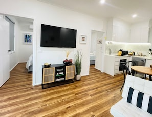 A modern living room with a flat-screen TV, a wooden console, and a sofa. - Brand-New Fernview 2BR w/ 2 Ensuites | Foothills (Ferntree Gully)