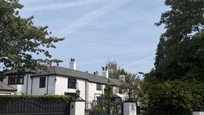 A white building with a gated entrance, surrounded by greenery.