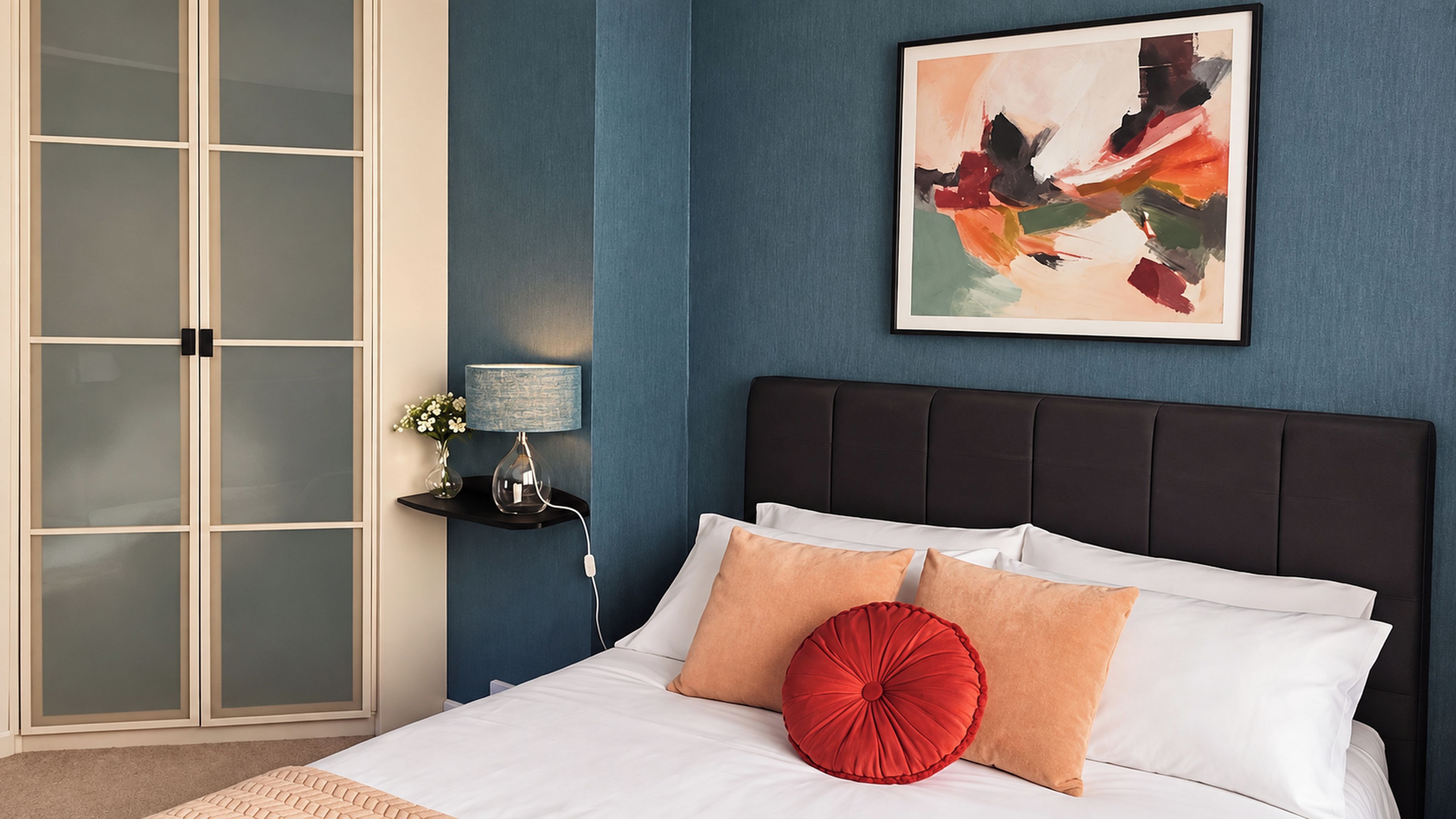 Une chambre à coucher avec un lit, une table de chevet, une lampe, un tableau et une porte coulissante.