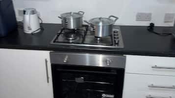 A kitchen with a stove, pots, a kettle, and a dishwasher.
