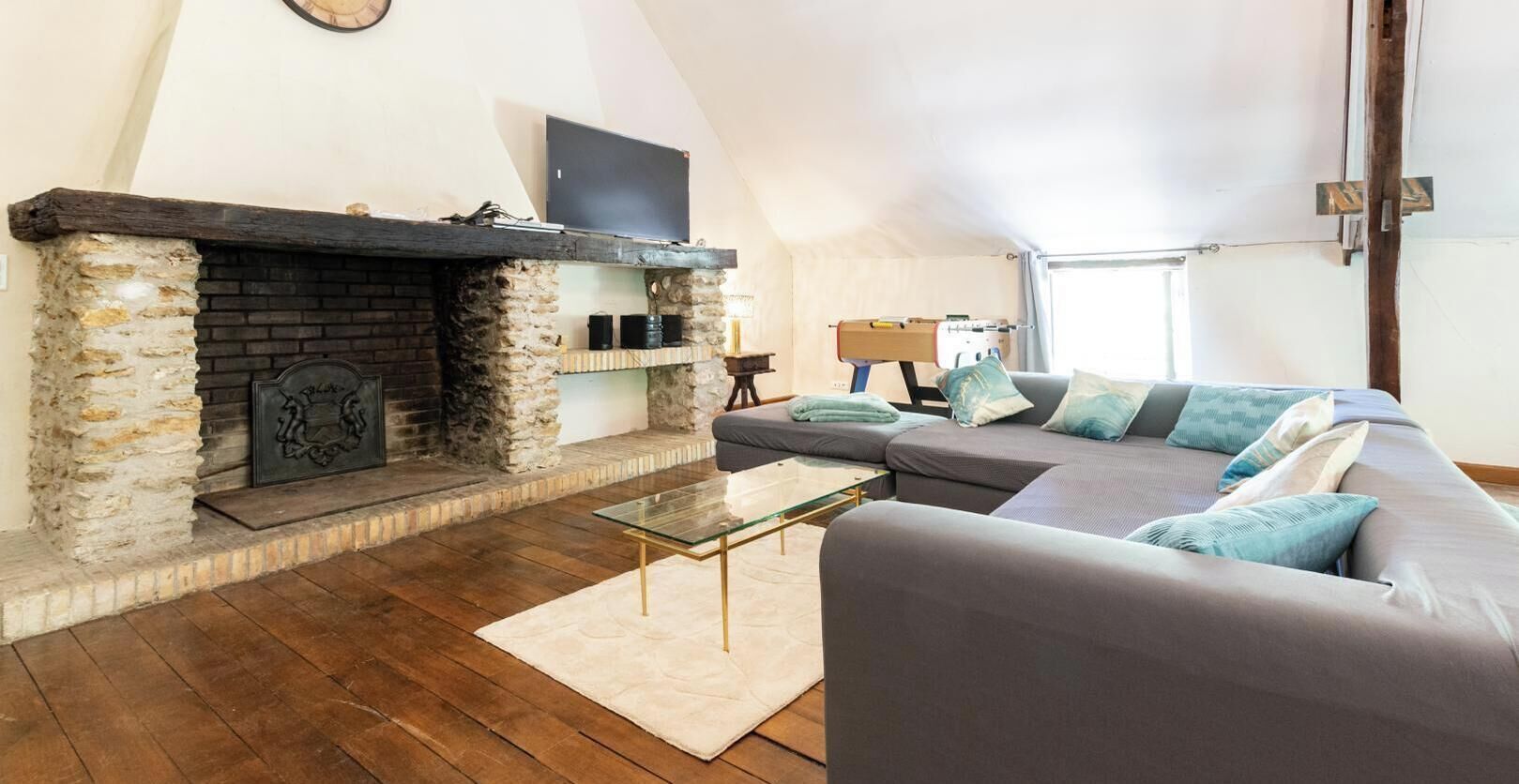 A living room with a fireplace, a sofa, a glass coffee table, and a lamp.