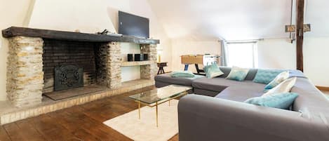 A living room with a fireplace, a sofa, a glass coffee table, and a lamp.
