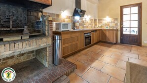 Uma cozinha com forno de tijolos, armários de madeira, micro-ondas e lava-louças.