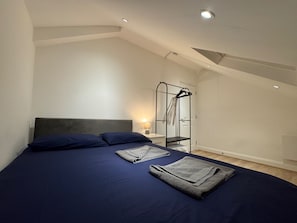 Un dormitorio con cama, armario y una lámpara en el techo.