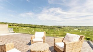Una terraza con mobiliario de mimbre y vista a un paisaje verde.