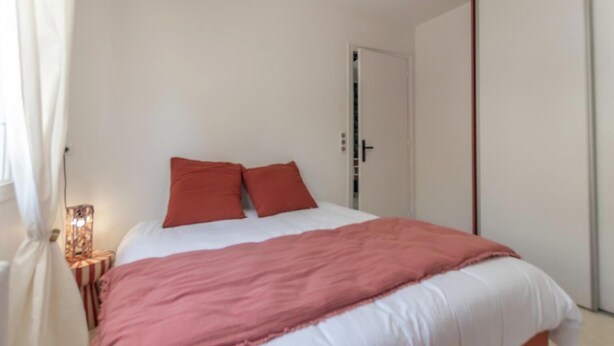 Un dormitorio con cama, mesita de noche, lámpara y armario.