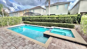 Une piscine rectangulaire dont les bords sont recouverts de carreaux, entourée d’une terrasse en briques.