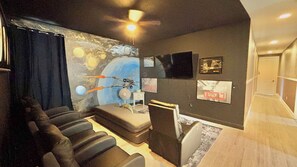 Une pièce dotée d’un ventilateur de plafond, d’un canapé, d’une petite table et d’un mur orné d’œuvres d’art.