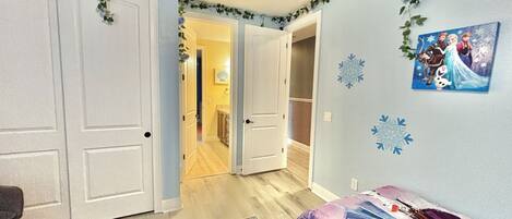Une chambre à coucher comprenant un lit, une commode et une porte donnant sur un couloir.