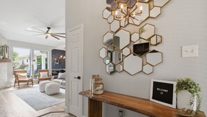 Un interior moderno con un muro de espejos hexagonales, un letrero de bienvenida y una consola de madera.