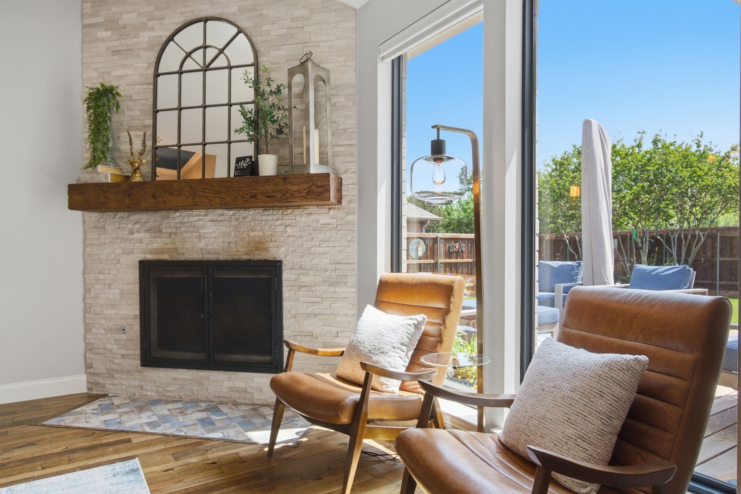Una sala de estar moderna con chimenea de piedra, sillones de cuero y un ventanal con vistas al exterior.