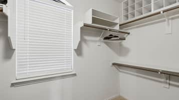 A closet with built-in shelves, a hanging rod, and a window with blinds.