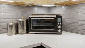 Cocina con horno tostador empotrado, dos recipientes de acero inoxidable y encimera blanca.