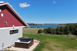 A house with a red roof and a hot tub in the backyard. - SaltWind Retreat | Bay Views Near Cavendish (Kensington)