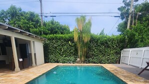 A rectangular swimming pool with a tiled deck in front.