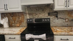 A kitchen with white cabinets, a black stove, and a marble countertop.