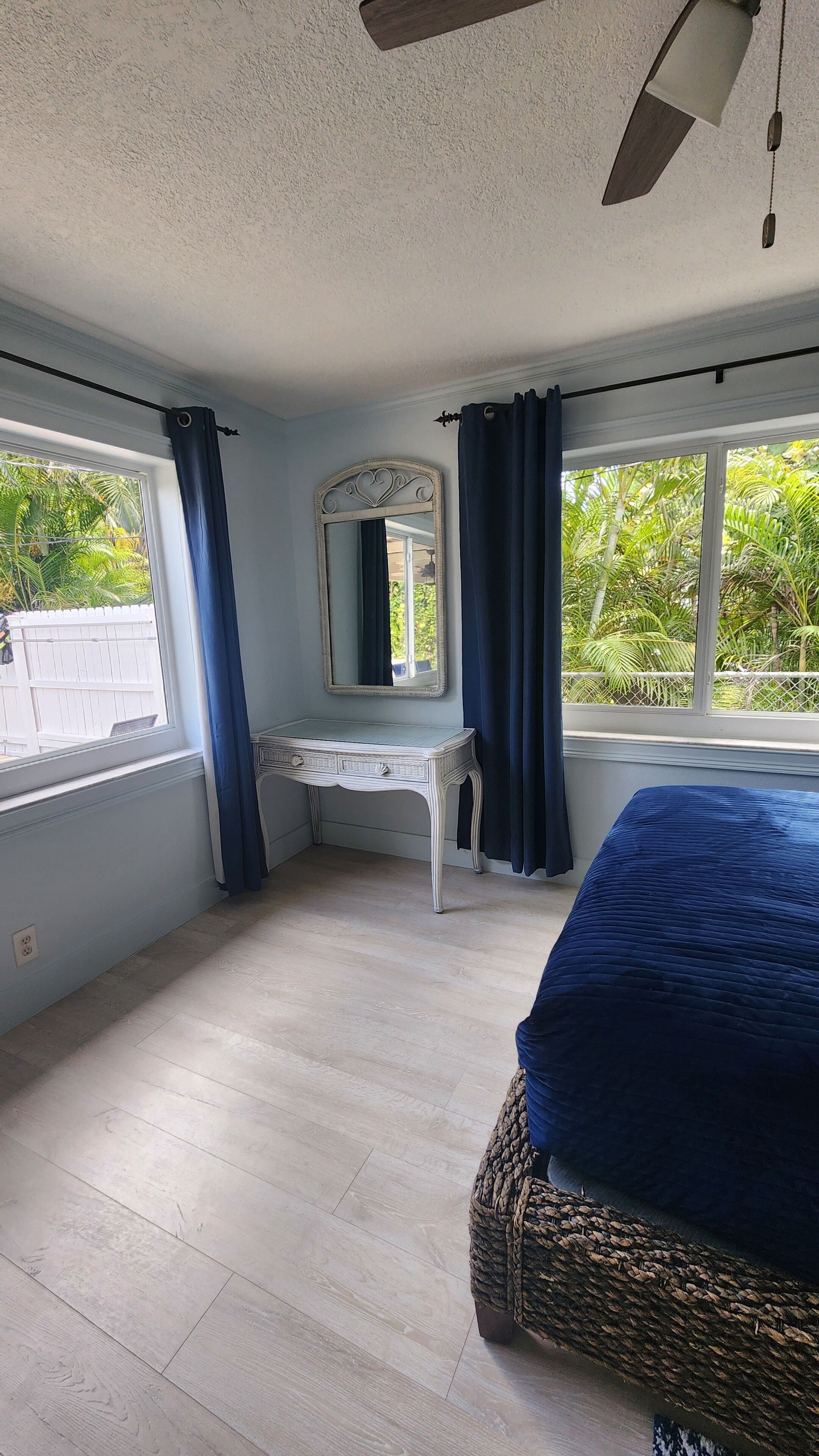 A bedroom with a bed, a dresser, a mirror, and a ceiling fan.