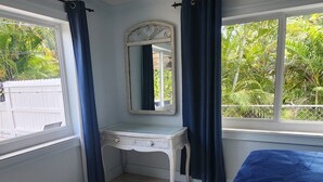 A bedroom with a bed, a dresser, a mirror, and a ceiling fan.