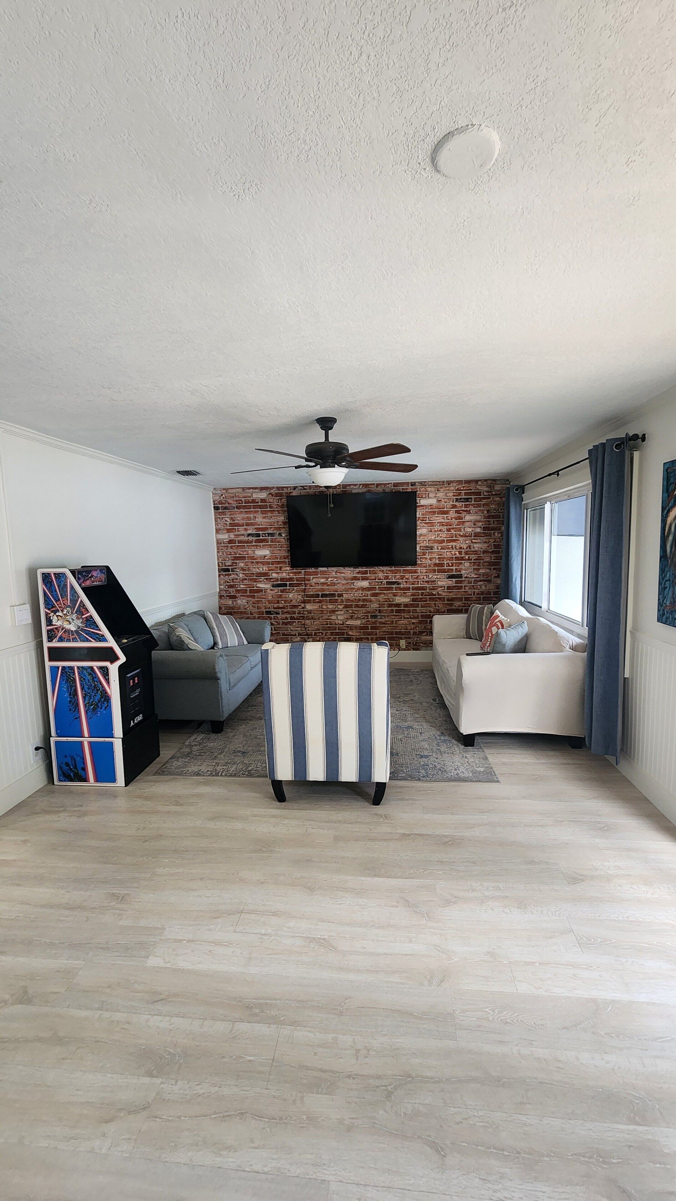 A living room with a brick wall, a ceiling fan, a flat-screen TV, and two sofas.
