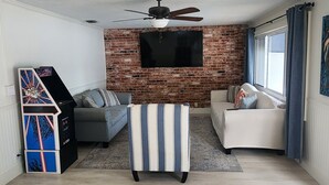 A living room with a brick wall, a ceiling fan, a flat-screen TV, and two sofas.