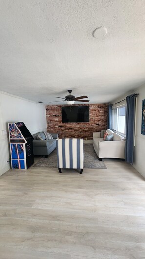 A living room with a brick wall, a ceiling fan, a flat-screen TV, and two sofas.