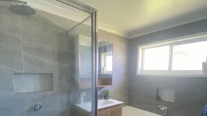 A modern bathroom with a glass shower enclosure, a freestanding bathtub, and a vanity with a mirror. -     Your Home Away From Home (Inverell)