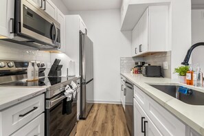 Eine moderne Küche mit Edelstahlgeräten, weißen Schränken und Holzboden.