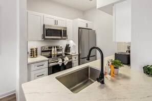 A modern kitchen with white cabinetry, stainless steel appliances, and a marble countertop. - Modern River Oaks Retreat / FIFA + Pool & Gym (Houston)