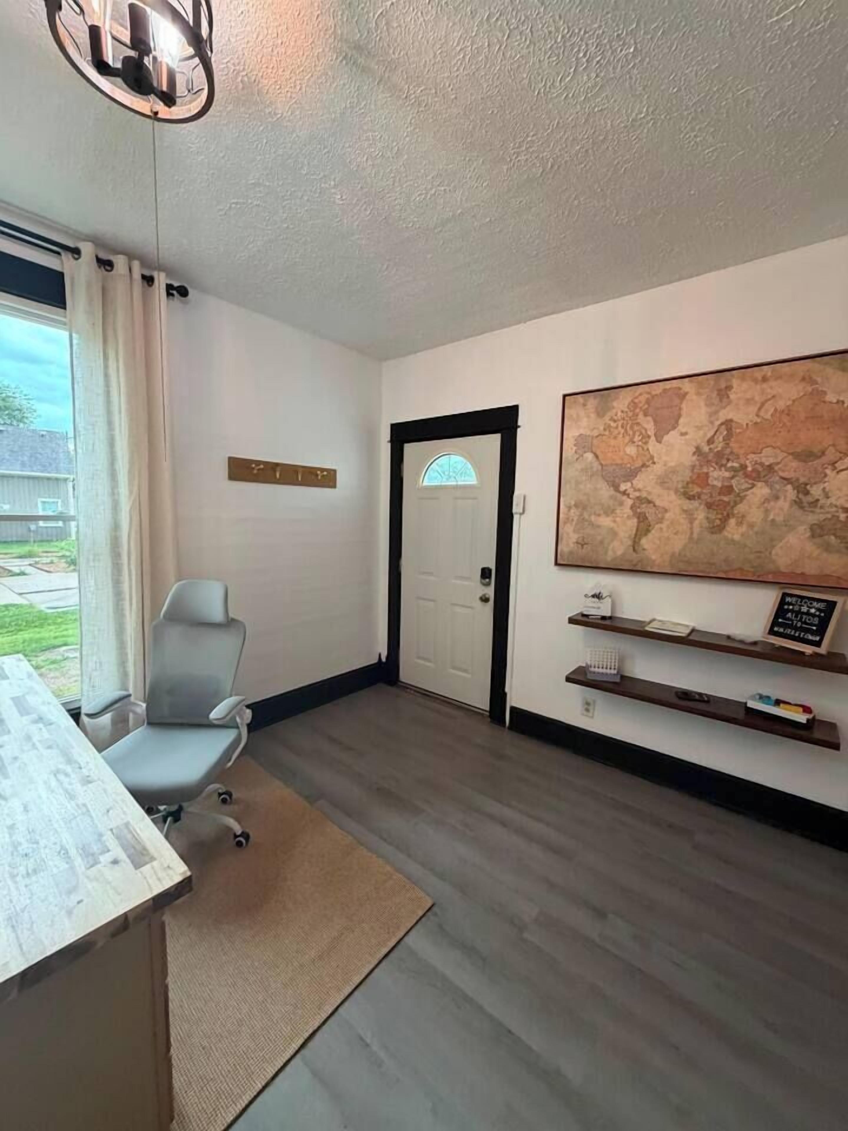 A room with a desk, a chair, a map on the wall, and a door.