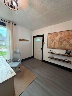 A room with a desk, a chair, a map on the wall, and a door.