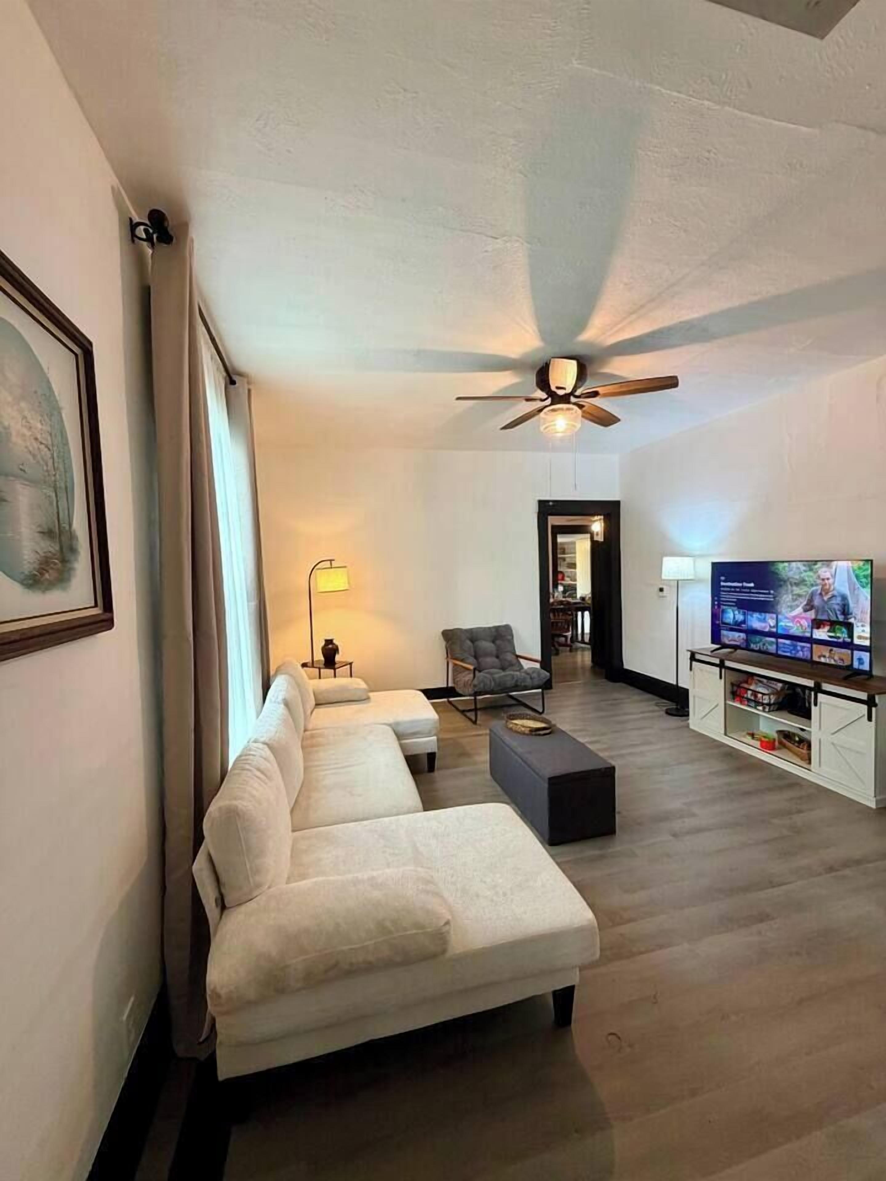 A modern living room with a sofa, a coffee table, a TV, and a ceiling fan.