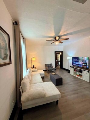 A modern living room with a sofa, a coffee table, a TV, and a ceiling fan.