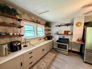 A kitchen with white cabinets, a built-in oven, a refrigerator, and a window with a view.