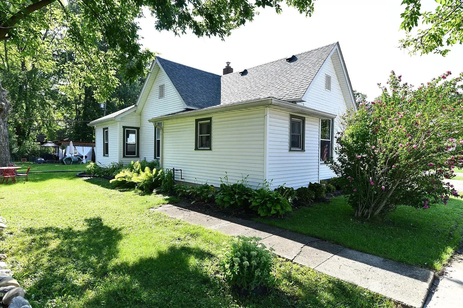 A two-story house with a front yard, a driveway, and a tree.