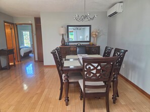 A dining area with a wooden table and chairs, a chandelier, and a mirror above the table.