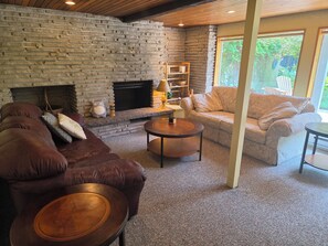 A cozy living room with a stone fireplace, leather sofas, and a coffee table.