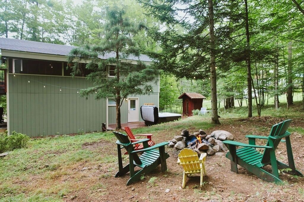 A cabin with a deck, outdoor seating, and a fire pit.