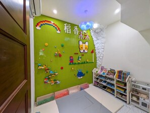 A children's play area with a green wall decorated with a rainbow, a dog, and other colorful figures. There are shelves with toys and books, and a play mat on the floor. - Wujie, Yilan private villa, ideal for families, friends and group stays. (Yilan County)