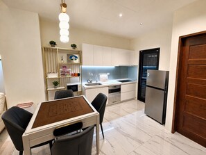 A modern kitchen with white cabinets, a stainless steel refrigerator, and a dining area with a table and chairs. - Wujie, Yilan private villa, ideal for families, friends and group stays. (Yilan County)