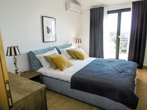 A bedroom with a bed, two bedside lamps, a framed picture on the wall, and a window with curtains. - Nicolina by Interhome (Poreč/Kaštelir)