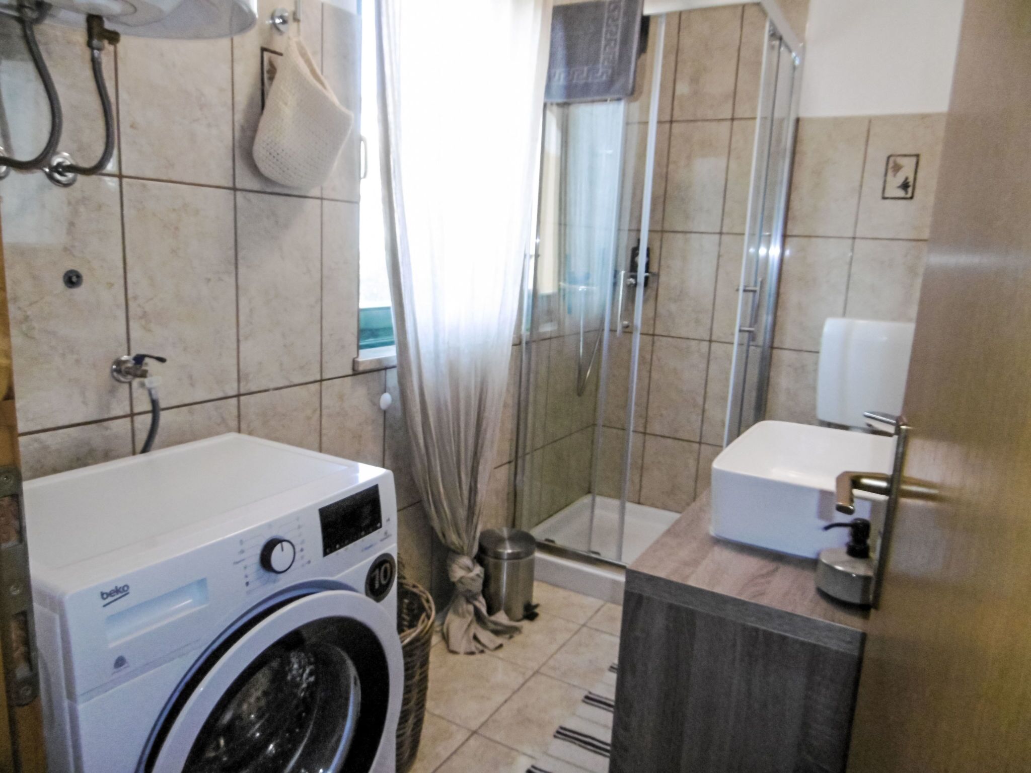 A compact bathroom with a washing machine, a shower enclosure, and a toilet.