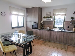 Una cuina moderna amb taula de vidre, caires i forn integrat.