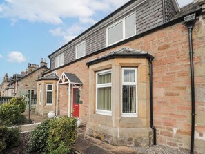 A row of terraced houses with brick facades, white-framed windows, and a red door. - Ballinreich by Interhome (Inverness)
