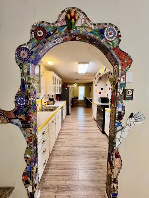A kitchen with a tiled backsplash, wooden flooring, and a central island. - The Terrace Above Main lLarge 4 bedroom House on Main St (Eureka Springs)