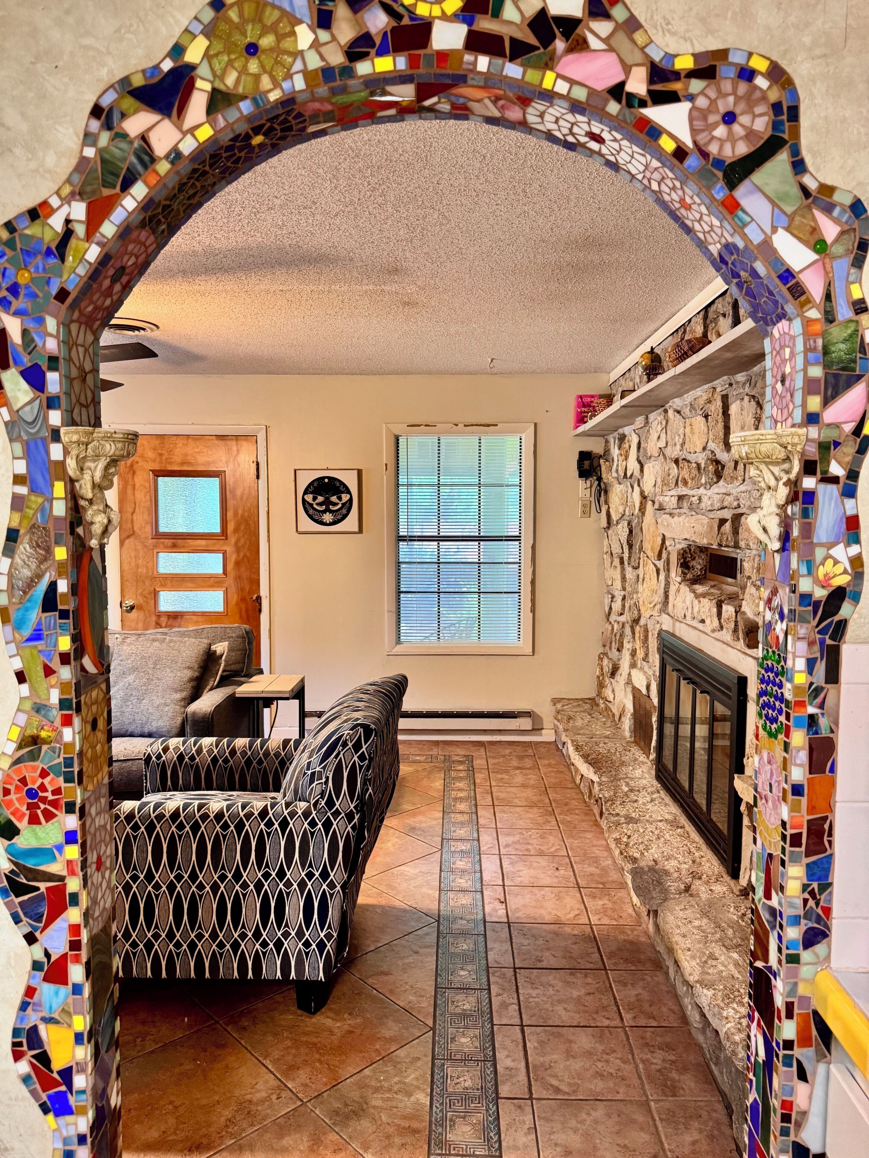 A living room with a fireplace, a sofa, a patterned rug, and a decorative archway.