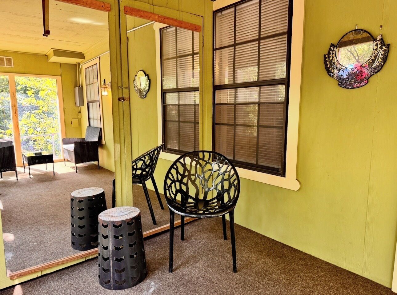 A room with a large mirror, two chairs, and a small table.