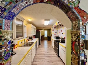 A kitchen with a tiled backsplash, a wooden floor, and a central island. - The Terrace Above Main lLarge 4 bedroom House on Main St (Eureka Springs)