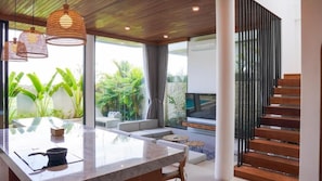 Un interior moderno con una isla de cocina, zona de estar y una escalera.